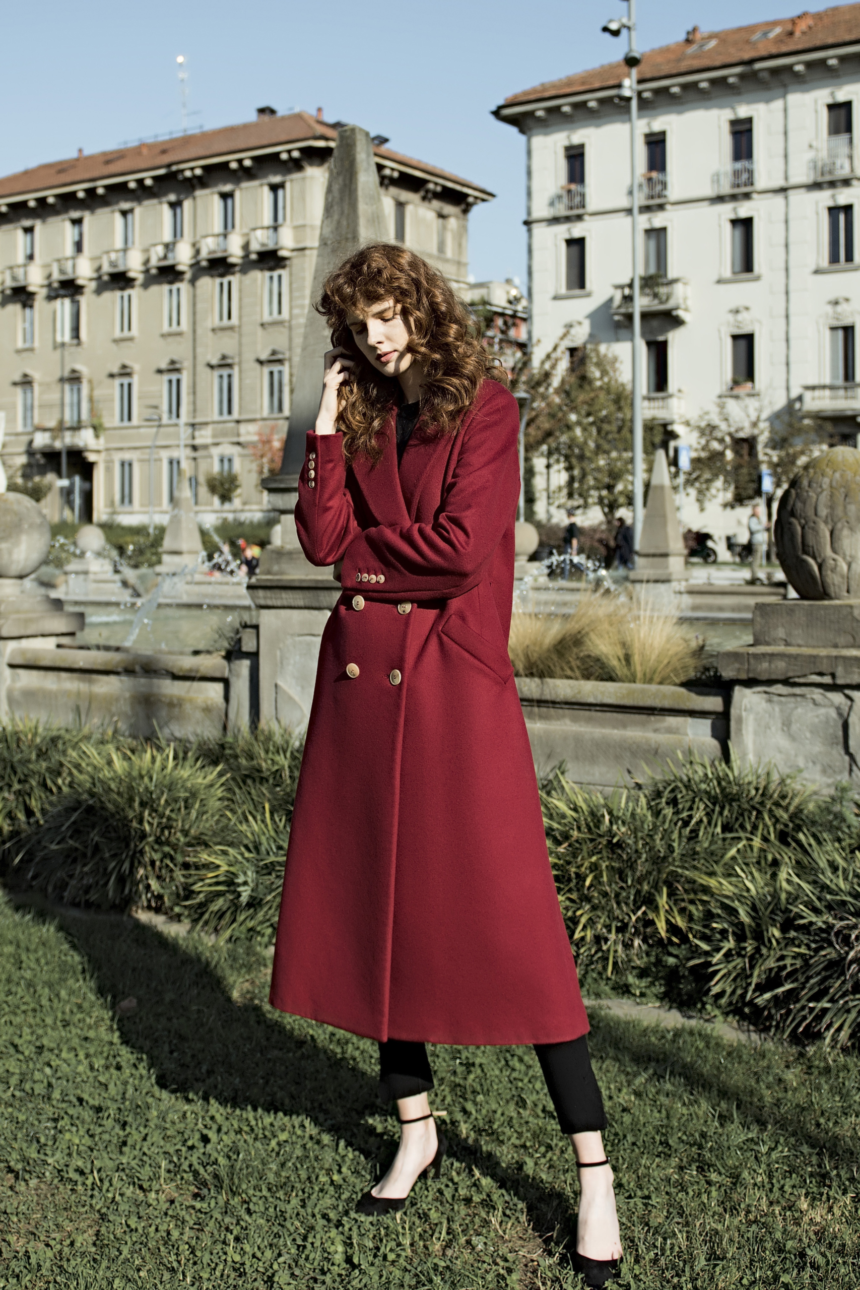 Elegant le Rú Diana coat in red, crafted from a blend of virgin wool and cashmere, showcased by a model in an outdoor setting, embodying a timeless design.